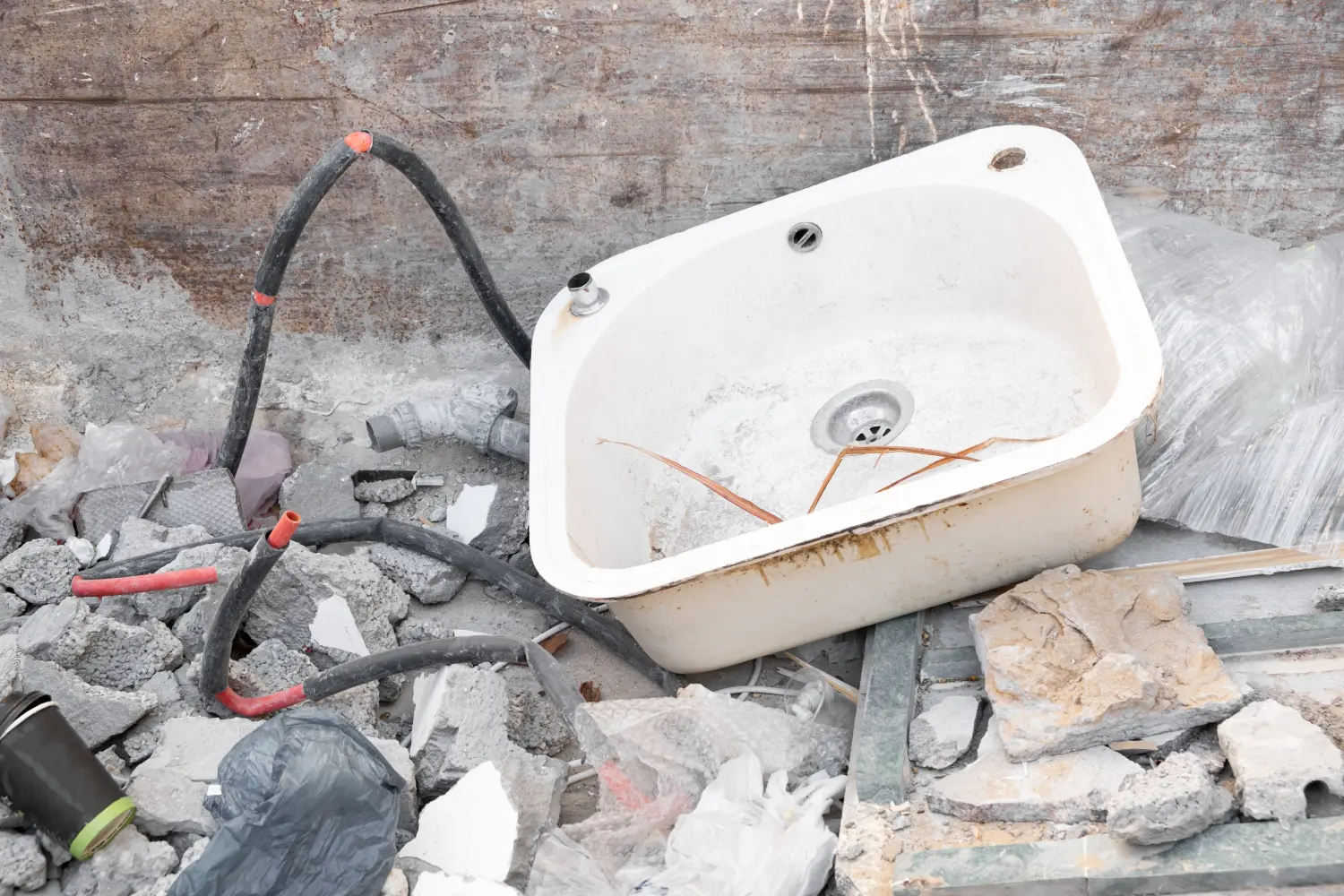 1A Qualitäts Umzüge GmbH - ein demontiertes altes Metallwaschbecken, das in einen Müllcontainer mit Bauschutt geworfen wurde